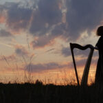 Eva-Maria Wallisch mit Harfe im Sonnenuntergang für Harp in the dark